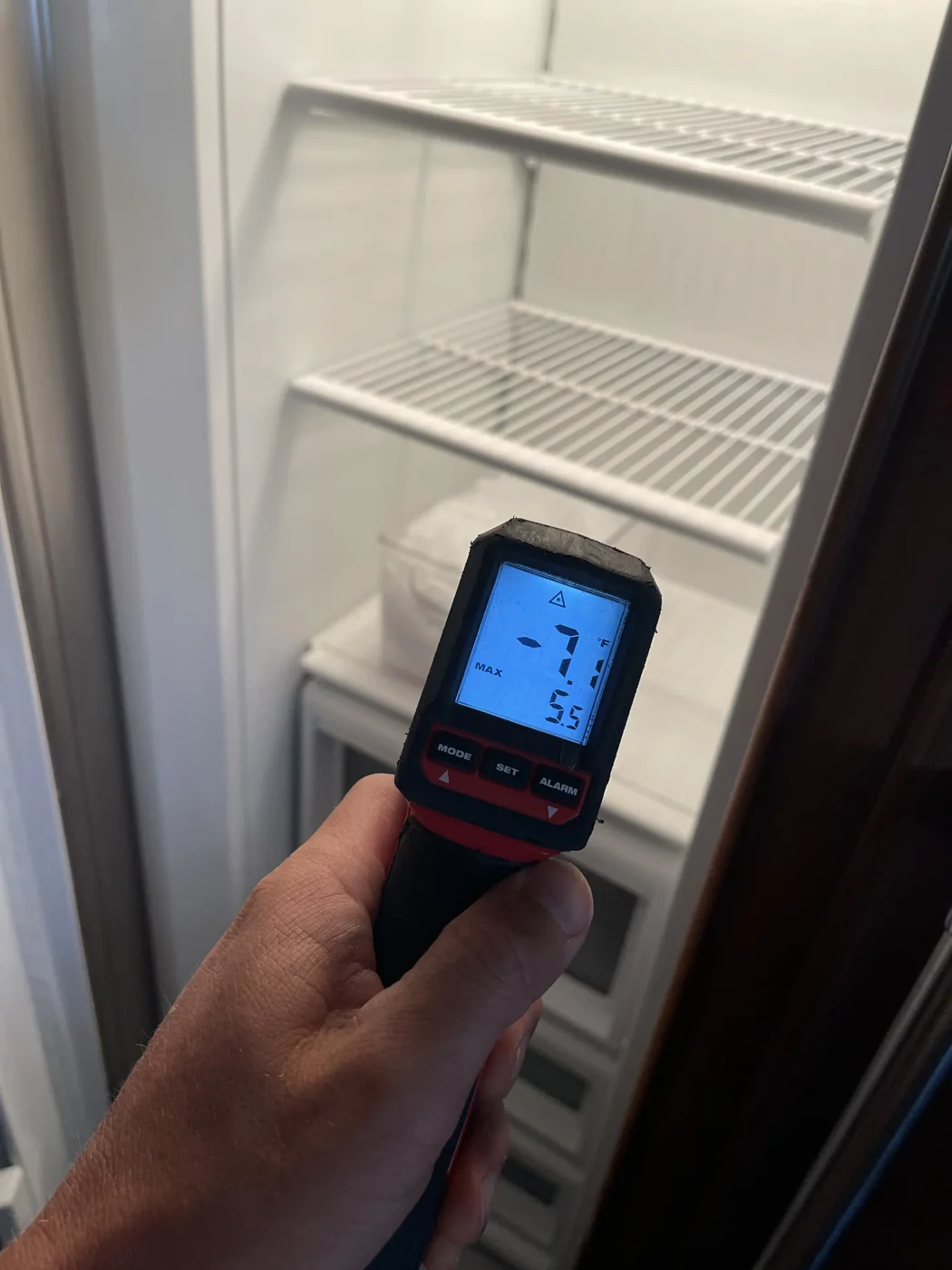 Infrared thermometer showing freezer temperature restored after repair